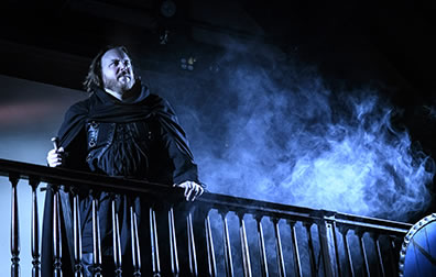 Production photo by Kenneth Garrett of Hamlet standing on the balcony with fog rising around him.
